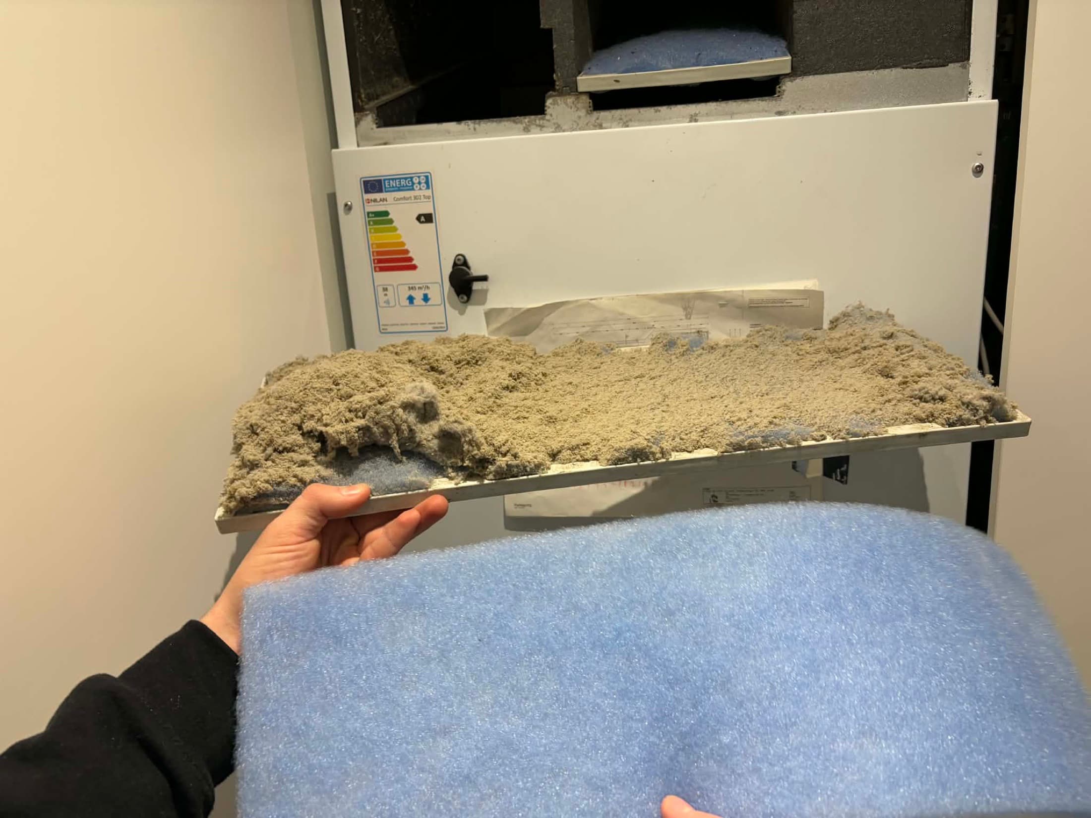 Filterbakke fra et Nilan ventilationsanlæg fyldt med støv ved siden af et nyt rent blåt filter