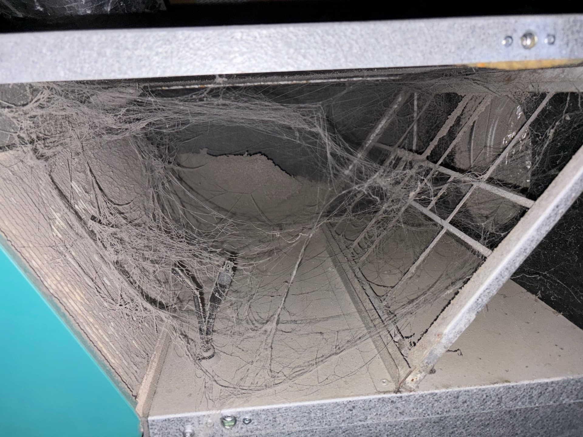 Indersiden af et ventilationsanlæg fyldt med spindelvæv og støv