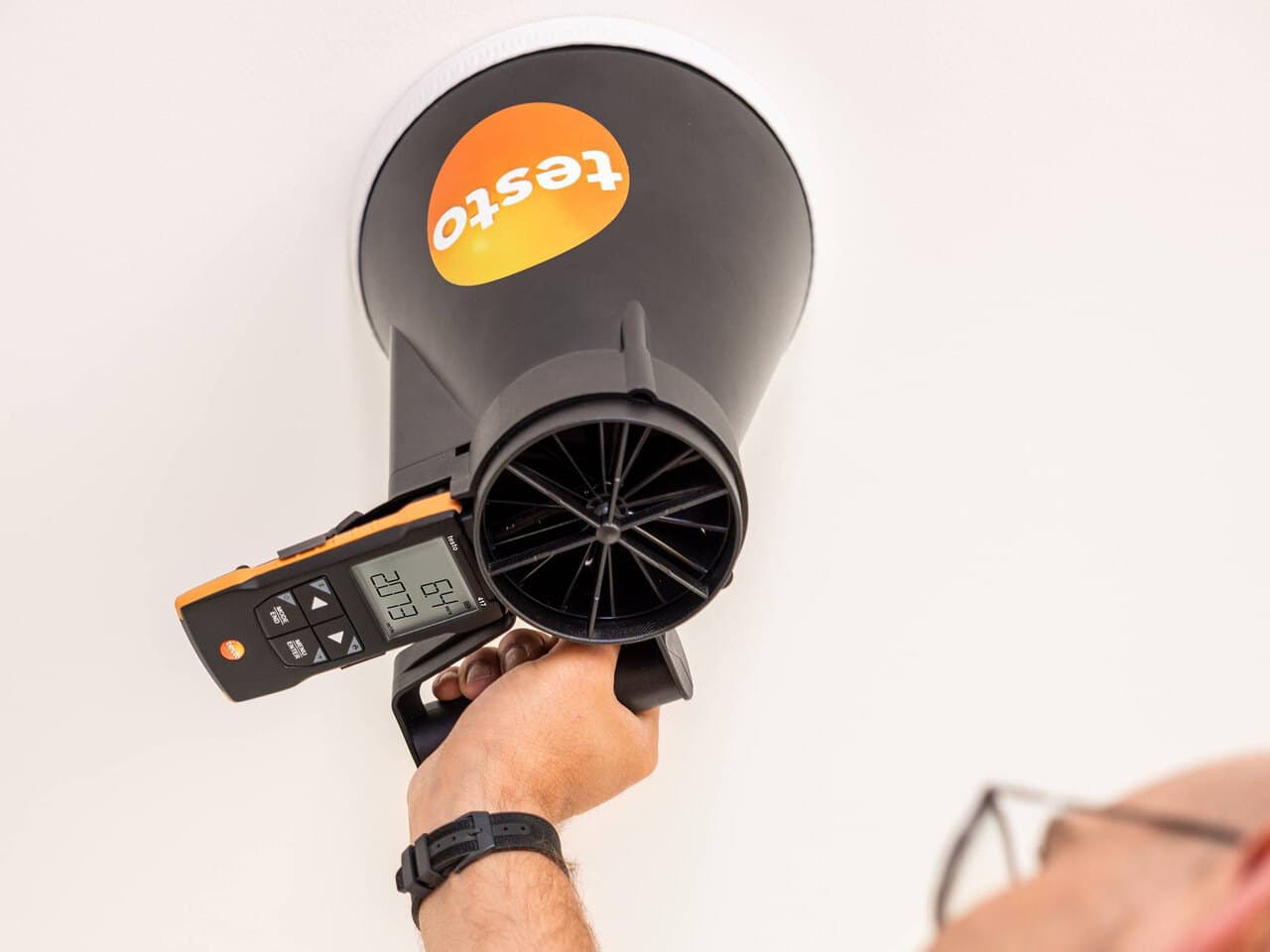 Tekniker måler og indregulerer luftmængden ved en indblæsningsventil med et testo flow-måleinstrument